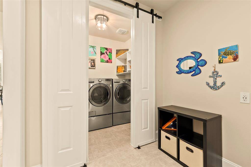 Mud room off the garage leads to the well-organized laundry room with washer and dryer included, accessible through sliding barn doors, creating a functional and inviting space.