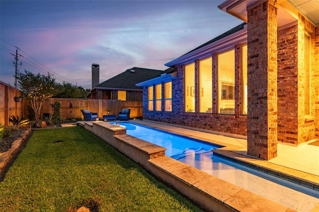 Sleek modern pool alongside fully bricked home with dramatic wall-of-windows. The warm solar landscape lighting adds to the inviting atmosphere. Pentair Intellibrite 5G Color LED Pool Light. Impeccable drainage in the backyard with PVC drains piped underground and PVC grates throughout the yard.