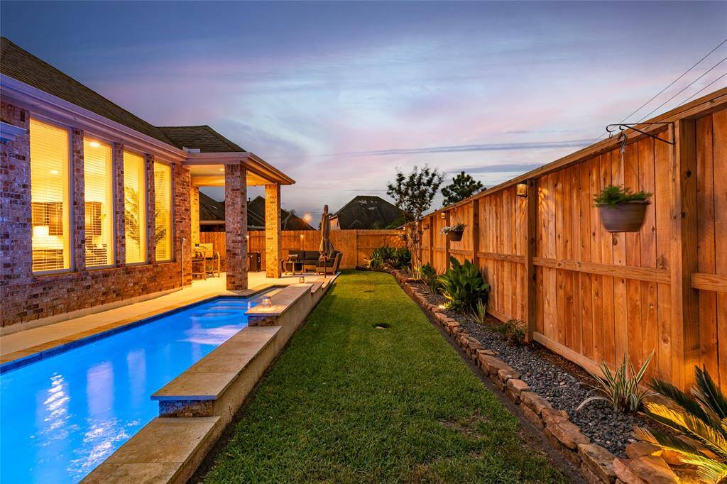 Take an early morning swim, or evening plunge! This inviting backyard features a sleek lap pool alongside the brick home and patio, perfect for entertaining. The space is bordered by a privacy fence with professional landscaping & solar lighting, offering a serene and private outdoor retreat.