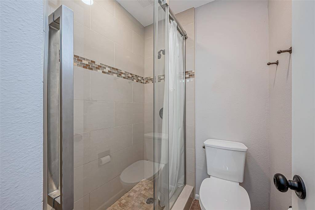 Floor to ceiling tile enclosed shower with sliding, frameless glass door.
