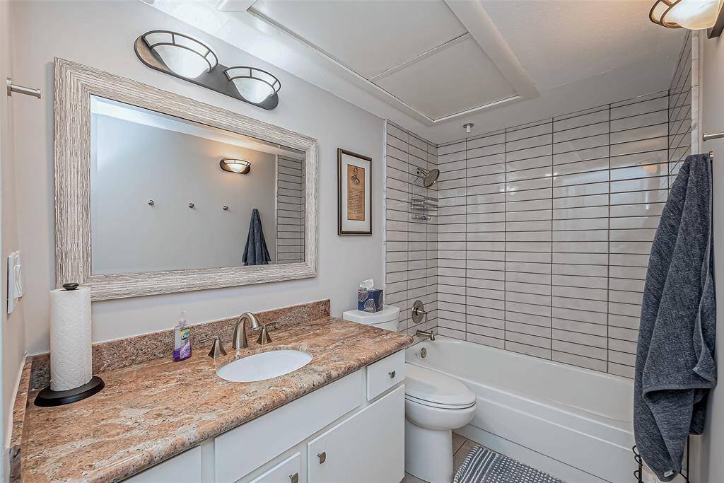 Secondary bath has exotic granite counters, brushed nickel finishes and a custom mirror.  Subway tile tub surround,