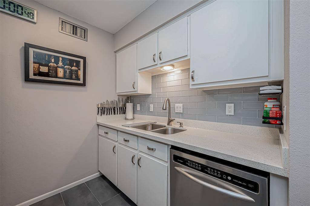 Updated kitchen features quartz countertops, glass tile backsplash, shaker cabinets with custom pulls.