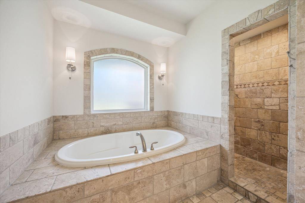 The bathroom features a large soaker tub and large walk in shower with a sitting shelf not pictured.