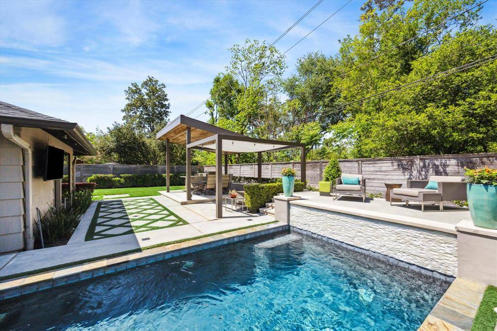 An outdoor view from behind the master suite overlooking the sundeck and waterfall of the pool.
