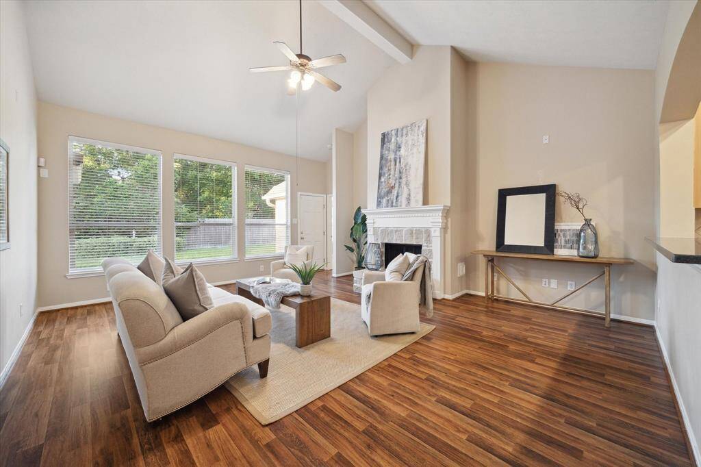 The Family Room has a vaulted ceiling with beam and an impressive stone fireplace with gas lighter, and custom wood mantlepiece.  Large windows overlook the paver stone patio and lush backyard.  Access the backyard through the door to the right of the windows.