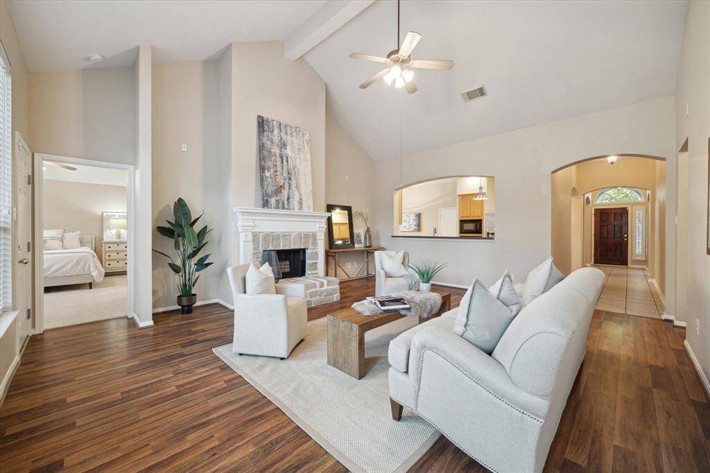 The Family Room is bathed in natural light.  Notice the arched openings to the kitchen and entry to the home.  Wood look laminate flooring is beautiful and durable. The primary suite is on the left in this photo.