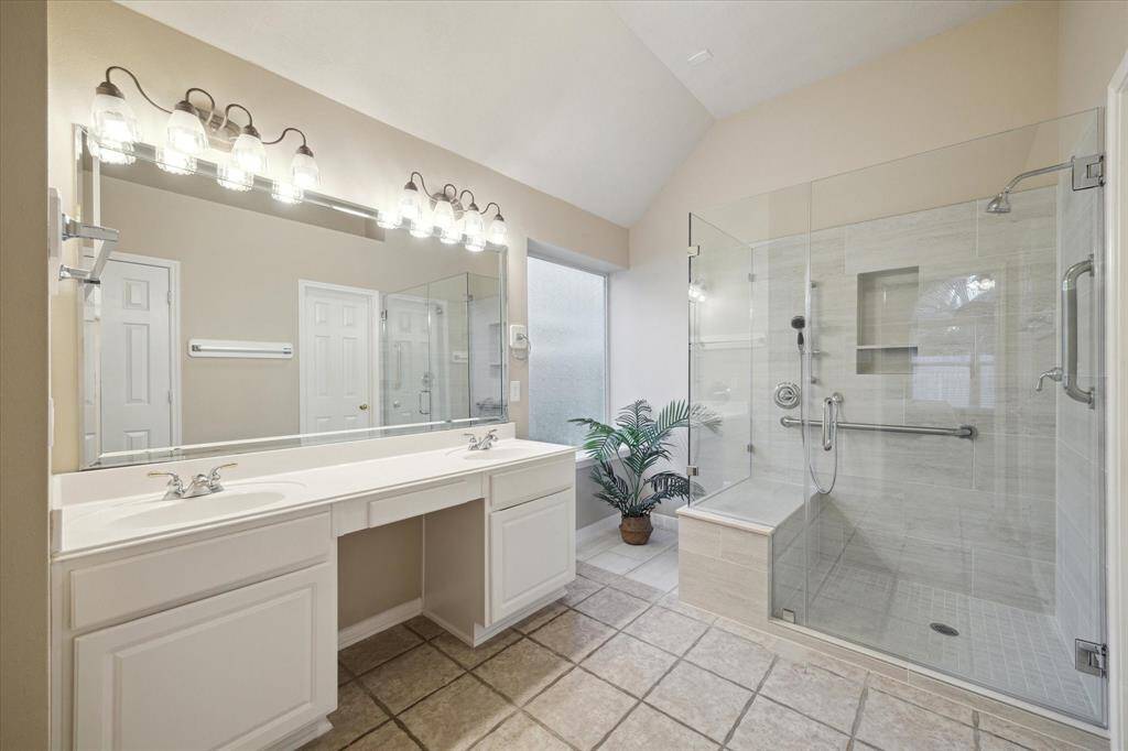 The luxurious primary shower was built in 2024.  Two shower heads on separate valves give options for bathing.  A bench seat, toiletry niche, and modern tile are functional and beautiful.  The seamless glass lets in light and sparkles.
