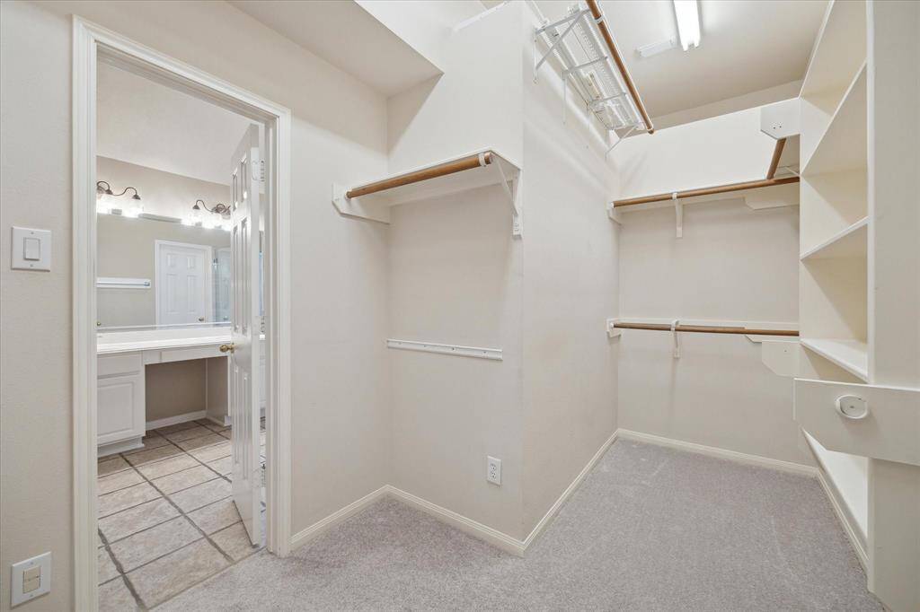 The primary walk in closet has built in shelves and wall upon wall of racks for hanging clothes. The high ceiling offers more storage above.  Spread out those hangers and enjoy seeing each item since there is so much space.