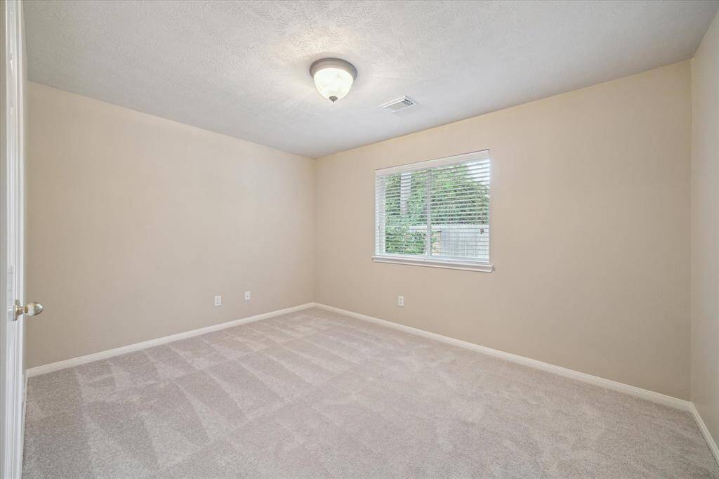 This secondary bedroom has a view of the backyard.  A closet is on the left in this photo.  All bedrooms have new carpet (April 2025) and all bedrooms are wired for a light and a ceiling fan.