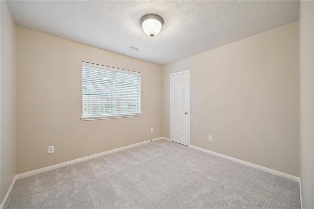 This secondary bedroom has a view of the side yard.  A walk in closet is present here.  All bedrooms have new carpet (April 2025) and all bedrooms are wired for a light and a ceiling fan.