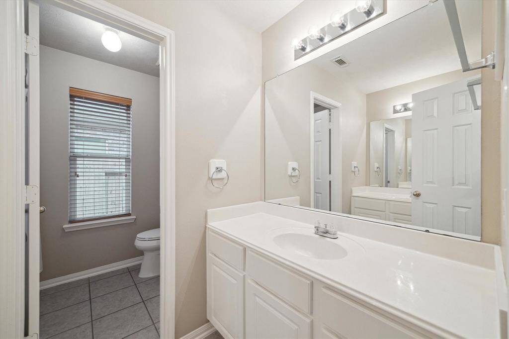 The spacious hall bathroom is divided into two rooms.  The tub and shower are located with the toilet and linen closet in the far room and the two vanities are in the foreground.