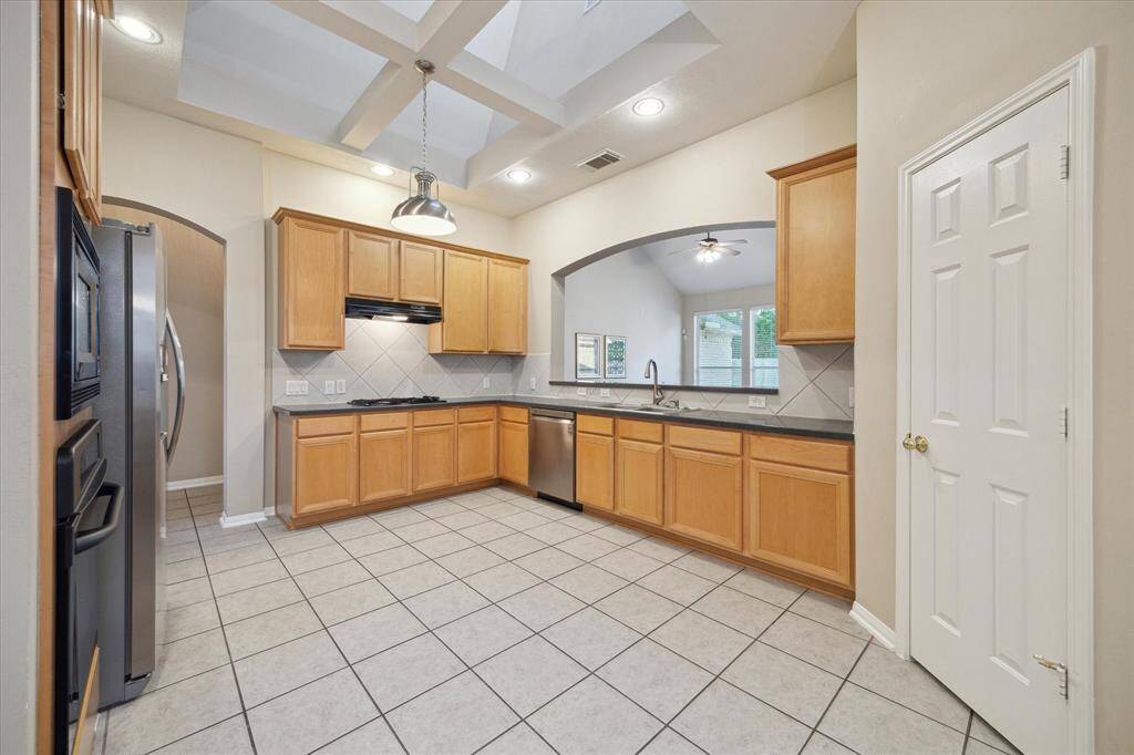 The expansive kitchen has plenty of room for many cooks.  To the right is a large walk in pantry.  An arched opening to the Family Room has a breakfast bar.  Notice the stunning open coffered ceiling skylight above.