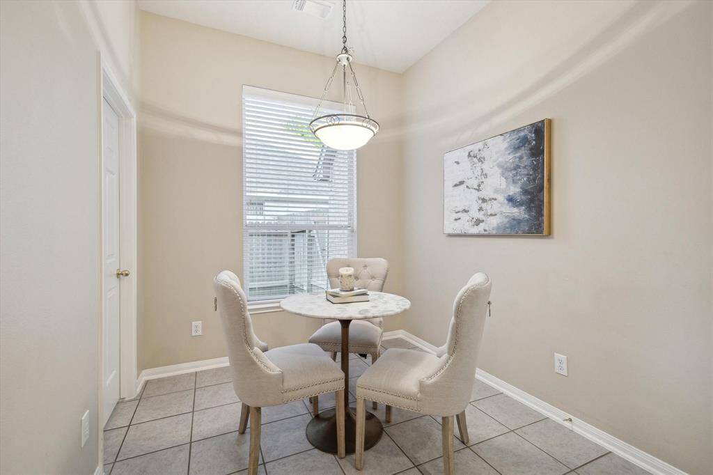 The light filled breakfast room has a large window and high ceiling.  An attractive light fixture has universal appeal. To the left is the utility room.