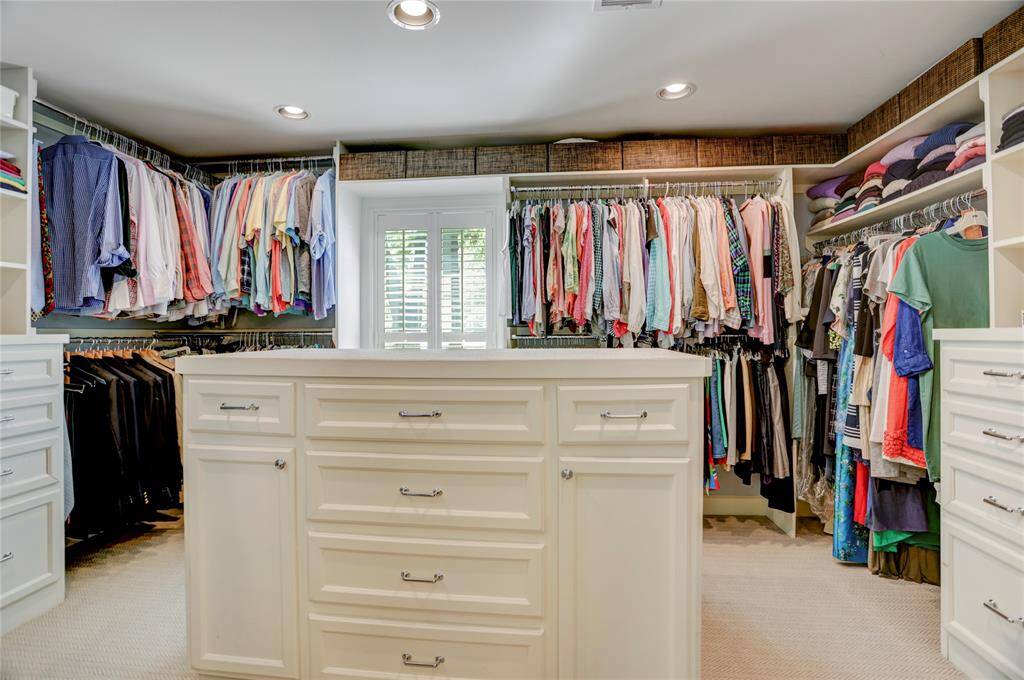 The oversized custom primary closet is a dream - so many built-ins, plenty of hanging space, natural light and a folding island with additional storage.