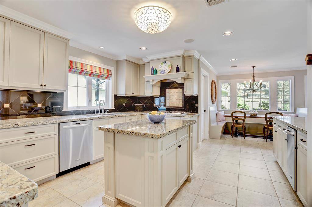 Another vantage point in the kitchen highlighting the custom vent hood cover with display shelving.  Toward the back windows is the breakfast nook with built-in banquette seating.
