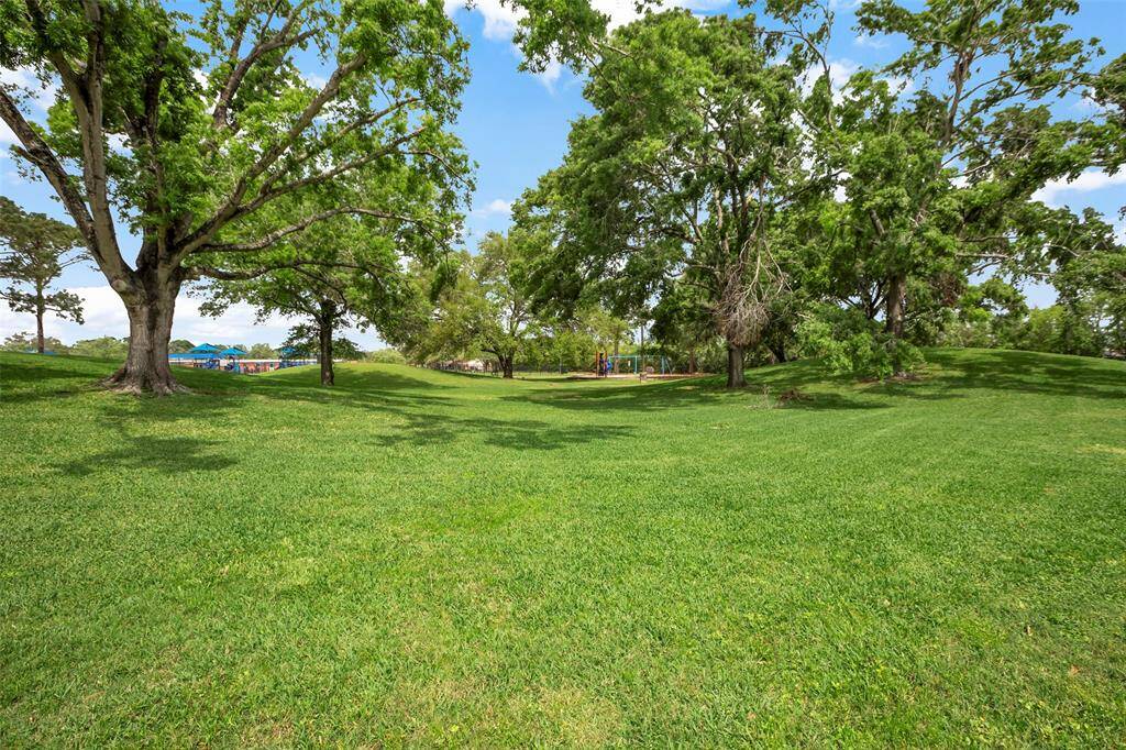 The surrounding areas are enveloped by mature trees and expansive lawns adorned with lush green grass, creating a serene and picturesque setting.