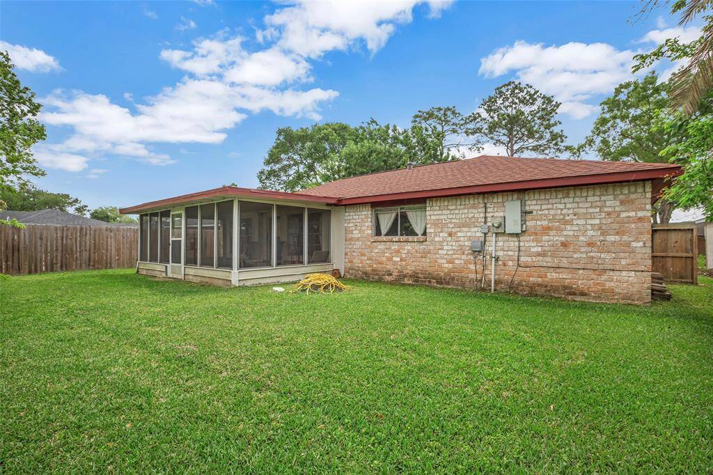 The expansive backyard is a serene retreat, featuring lush green grass and ample space for outdoor activities, all within the privacy of a tall wooden fence and wire.