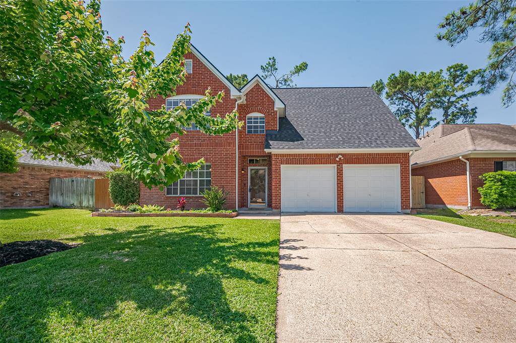 This charming two-story brick home features a neatly manicured front yard, a wide driveway leading to a double garage, and a welcoming entrance. The property is surrounded by mature trees, adding to its curb appeal.