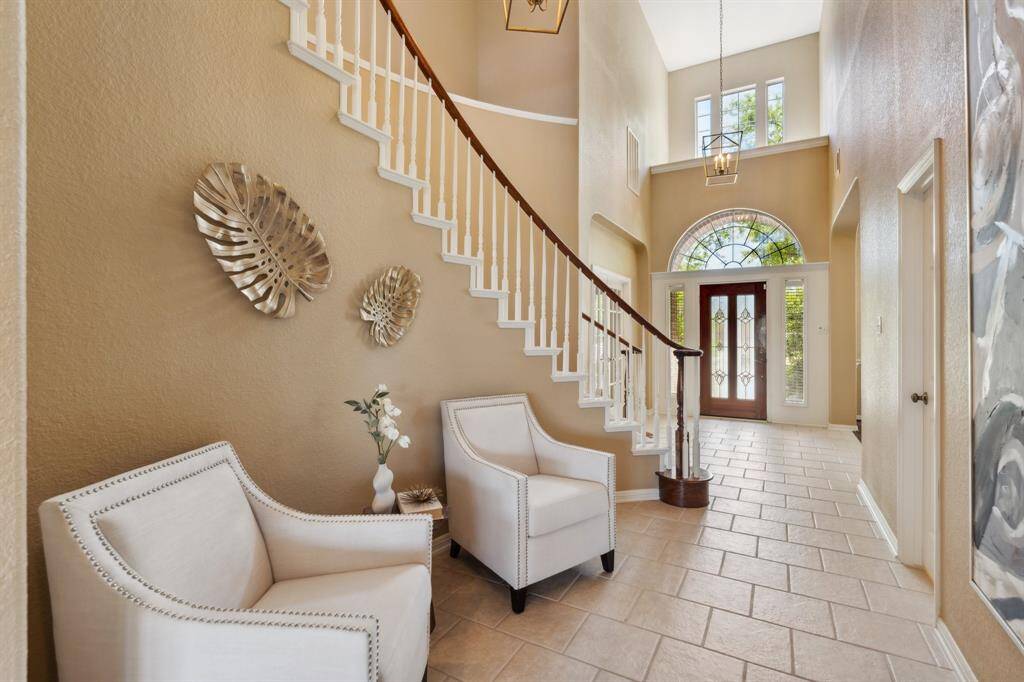 Step into the grand foyer where soaring ceilings and a sweeping curved staircase set the tone for elegance.