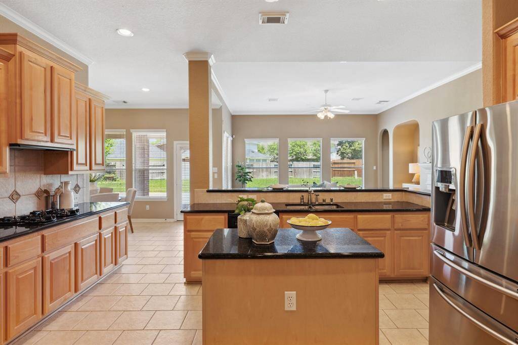 The chef-inspired kitchen includes granite countertops, a gas cooktop, an island, and plenty of cabinetry.