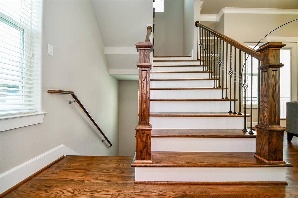 Warm hardwood stairs with custom wrought iron railing and rich wood trim details—an architectural highlight.