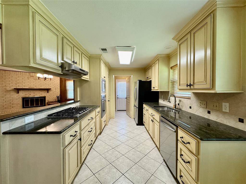 All stainless steel appliances in the kitchen, including gas stove, wall-mounted oven/microwave, dishwasher, and French door refrigerator.