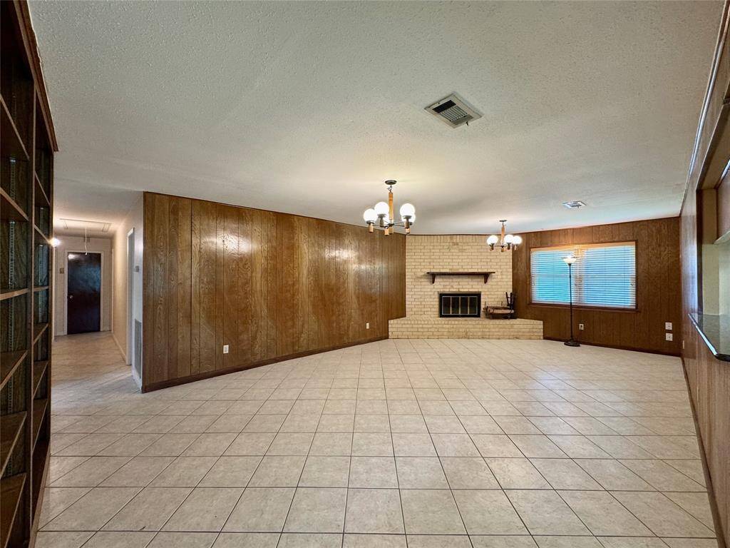 Large, warm, and inviting living room, with wood-paneling and fireplace.