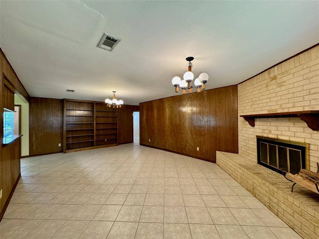 Large, warm, and inviting living room, with wood-paneling and fireplace.