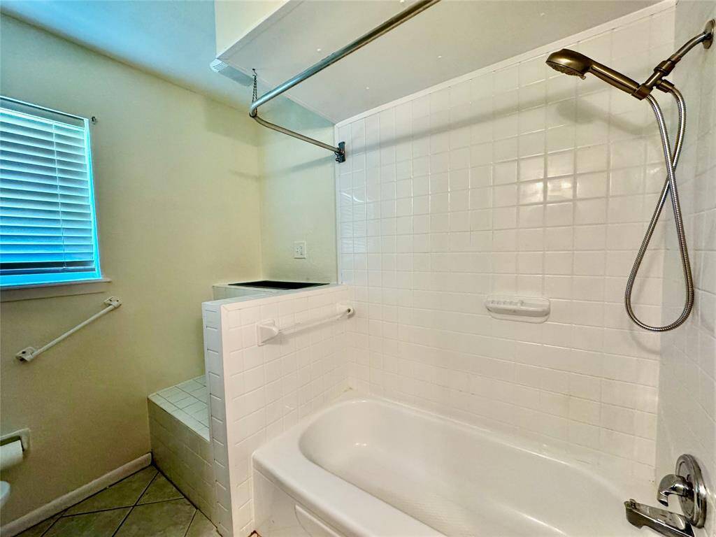 Hallway bathroom features two sinks, long vanity, full tub, commode, and ample storage.