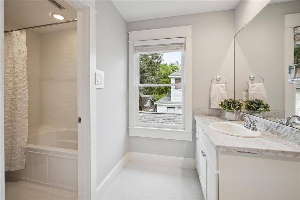 Another view of the hall bath with a large window allowing in natural light.