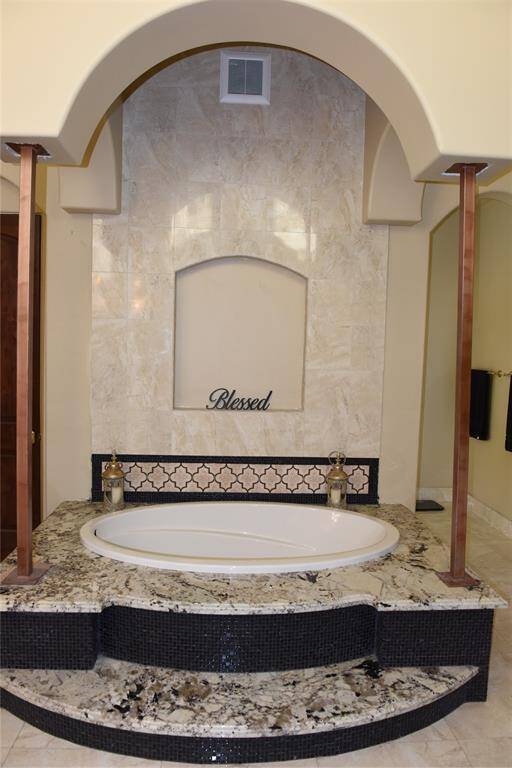 antique brass faucets include rainfall shower head, signature shower head and handheld shower head in this luxury walk in shower. porcelain floor and walls