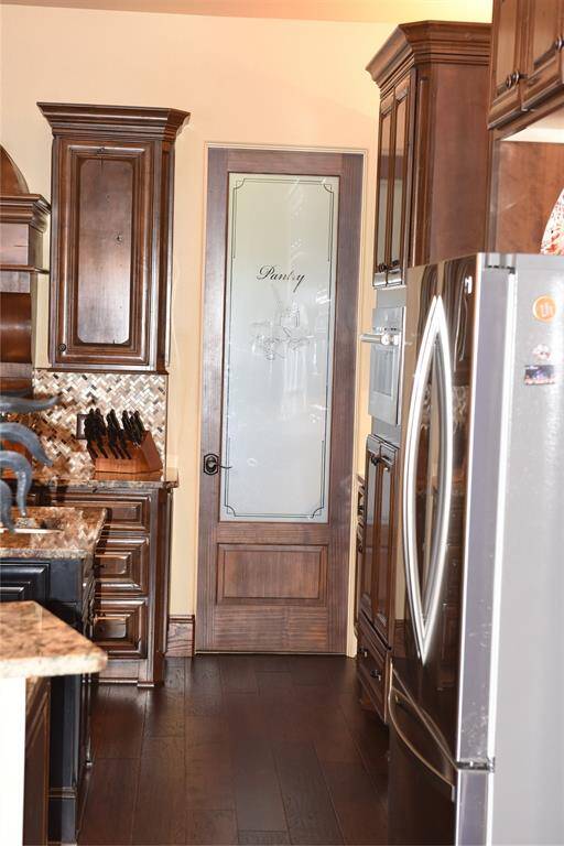 Kitchen with bar and spacious island with vegetable sink, granite countertop, on hard wood floors and custom wood beams.