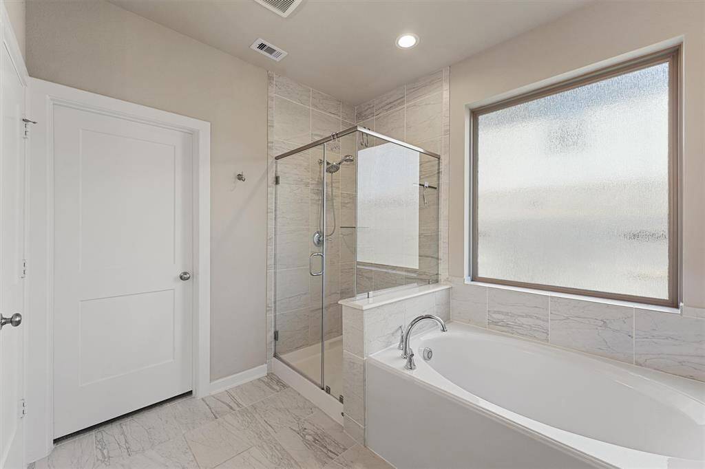 Unwind in the primary suite, featuring a separate soaking tub and shower for relaxation.