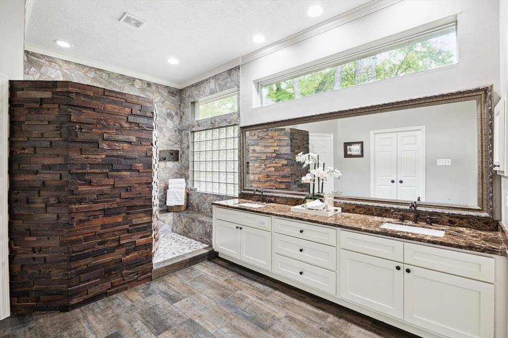 Updated primary bath with dual sink vanity and large stone accent shower.  Transome windows allow the natural light to carry through.