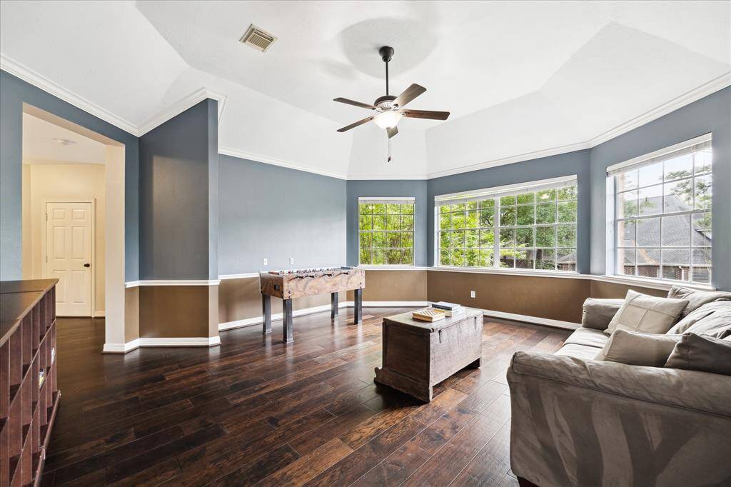 The spacious game room with wood floors, ceiling fan, wall of windows