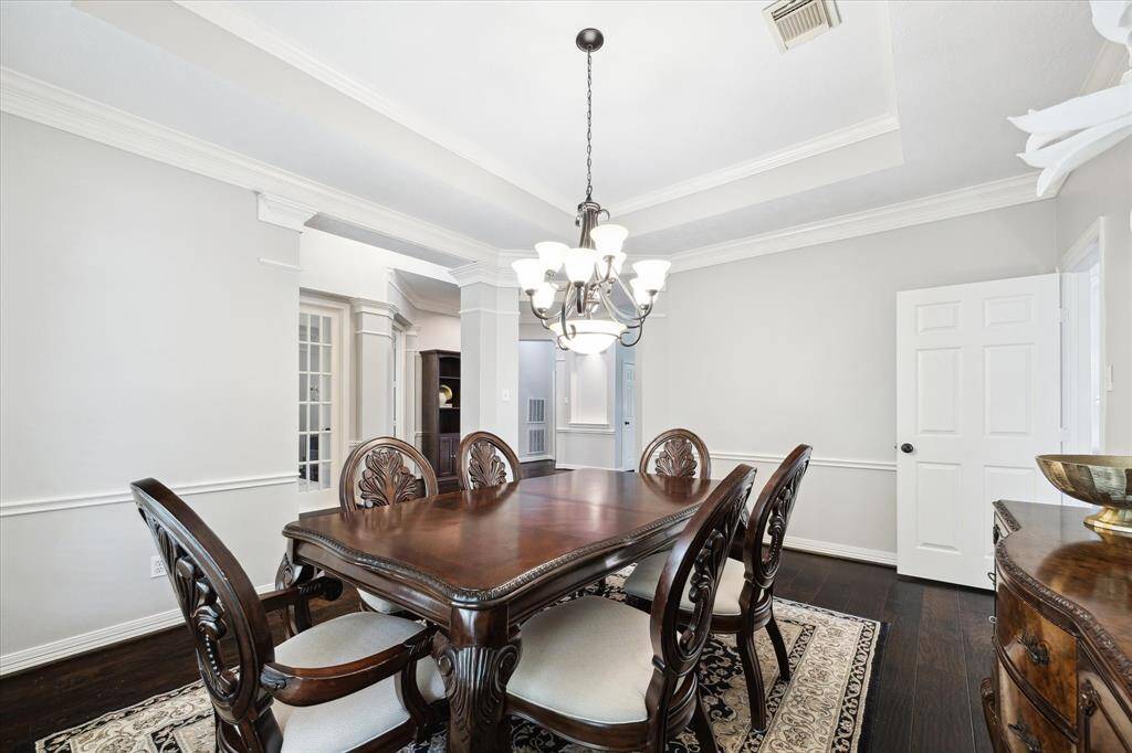 The room features elegant wood floors, chair railing, crown molding, and a trey ceiling.
