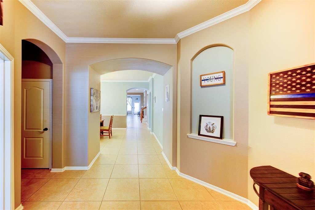 Extended tile entry featuring arches, crown molding, art niche