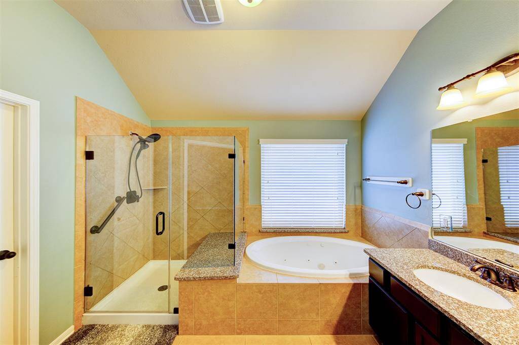 The ensuite bath features a separate oversize shower with seat & a jetted tub - a spacious walk-in closet is at the door on the left