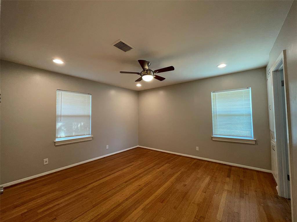 Spacious primary room with wood floor and ceiling fan to keep you cool in summer.