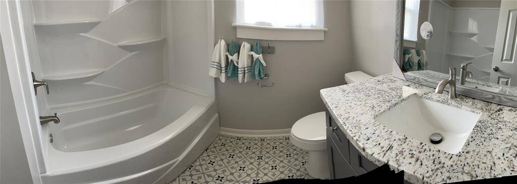 Remodeled primary bathroom with granite counter top and bath/shower combo.