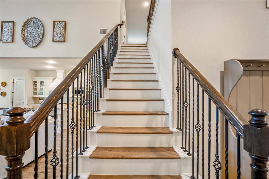 Grand staircase with custom iron balusters and warm wood treads makes a striking statement and sets the tone for the elevated design throughout the home.