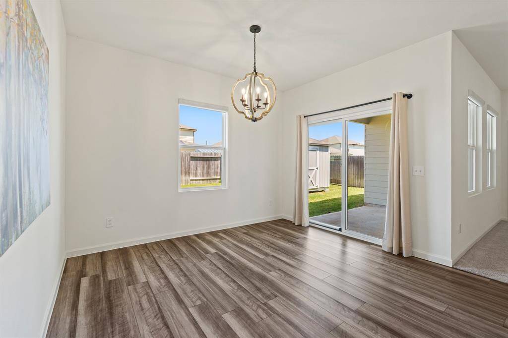 The variegated wood-like flooring continues into the Breakfast Room. Natural light spills into the space making it feel light and bright thanks to the rear facing window and sliding glass door that leads to the Back Patio.