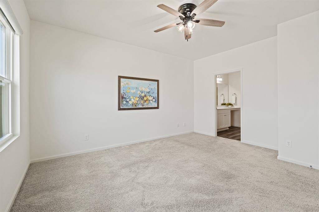This space is grand in size and can accommodate additional storage pieces and a TV if desired. A sneak peak of the Primary Bath can be seen ahead.