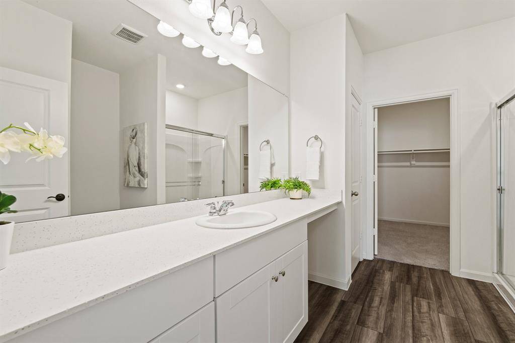 Relax and unwind in the comfort of this elegant Primary Bath. The beautiful, wood-like flooring continues through the space providing an anchor to the light and bright room. The spacious closet can be seen directly ahead.