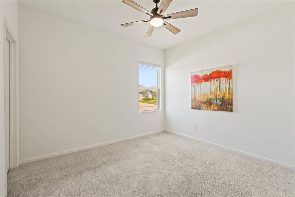This Secondary Bedroom boasts plush carpeting, a side-facing window, 5-blade ceiling fan, and a walk-in closet. Both Secondary Bedrooms share the Full Bathroom located right down the hall.