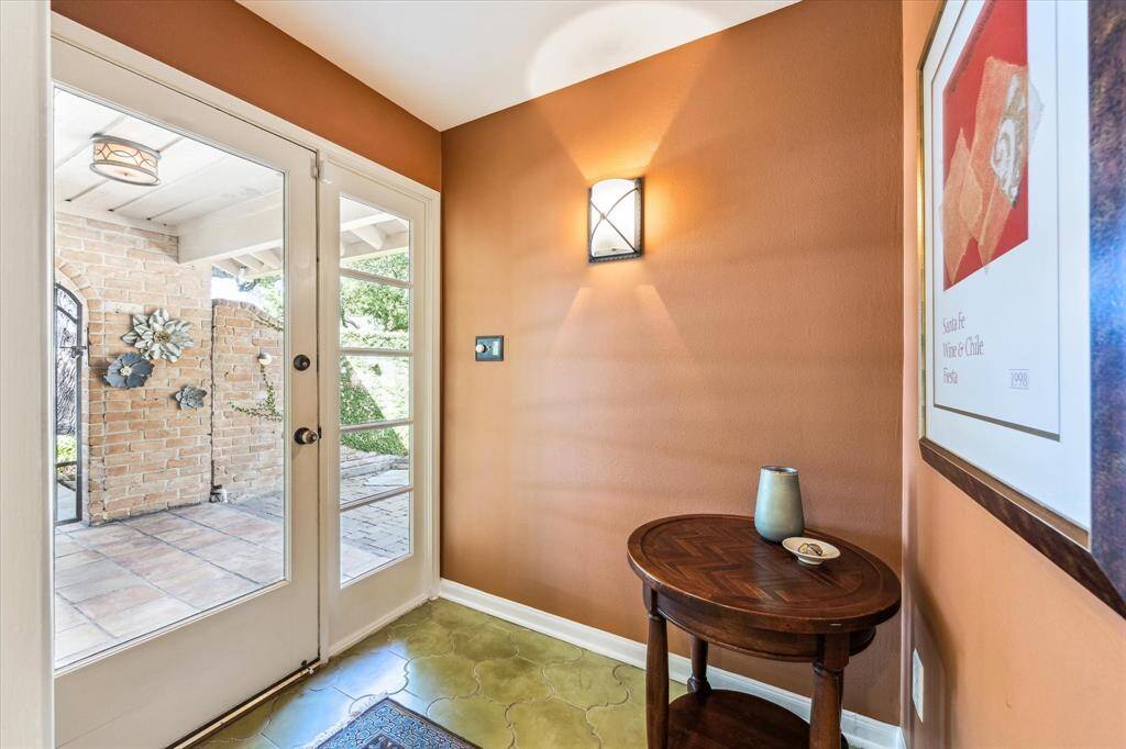 The formal entry features a striking glass door that floods the space with natural light and offers a clear view of the peaceful courtyard beyond, creating a seamless connection between indoors and out