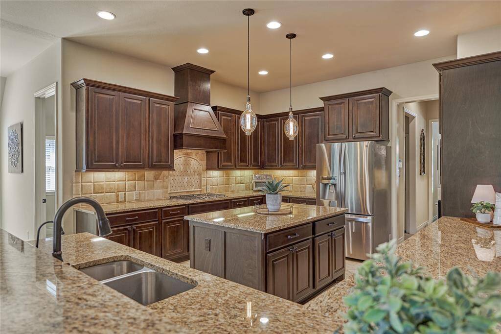 The personalized hood and backsplash, combined with the pendant lighting, create a cozy and welcoming feeling to this kitchen.