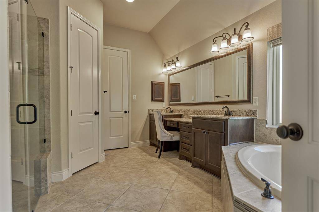 The primary bathroom features dual sinks, a vanity, a soaking tub, and a spacious shower with a bench.