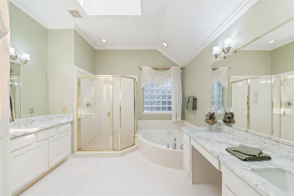 Updates include Carrera Marble countertops, new sinks, and large, modern porcelain flooring.  Note the skylight bringing in so much natural light! Drapery has recently been removed for a cleaner, more modern look.