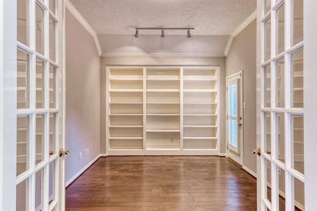 French doors keep this study private when closed. Or use as a flex space - maybe a TV room or a playroom.  The full wall of shelves will always come in handy for storage or to display your book collection. The walled in atrium is accessed through the door on the right in the picture.